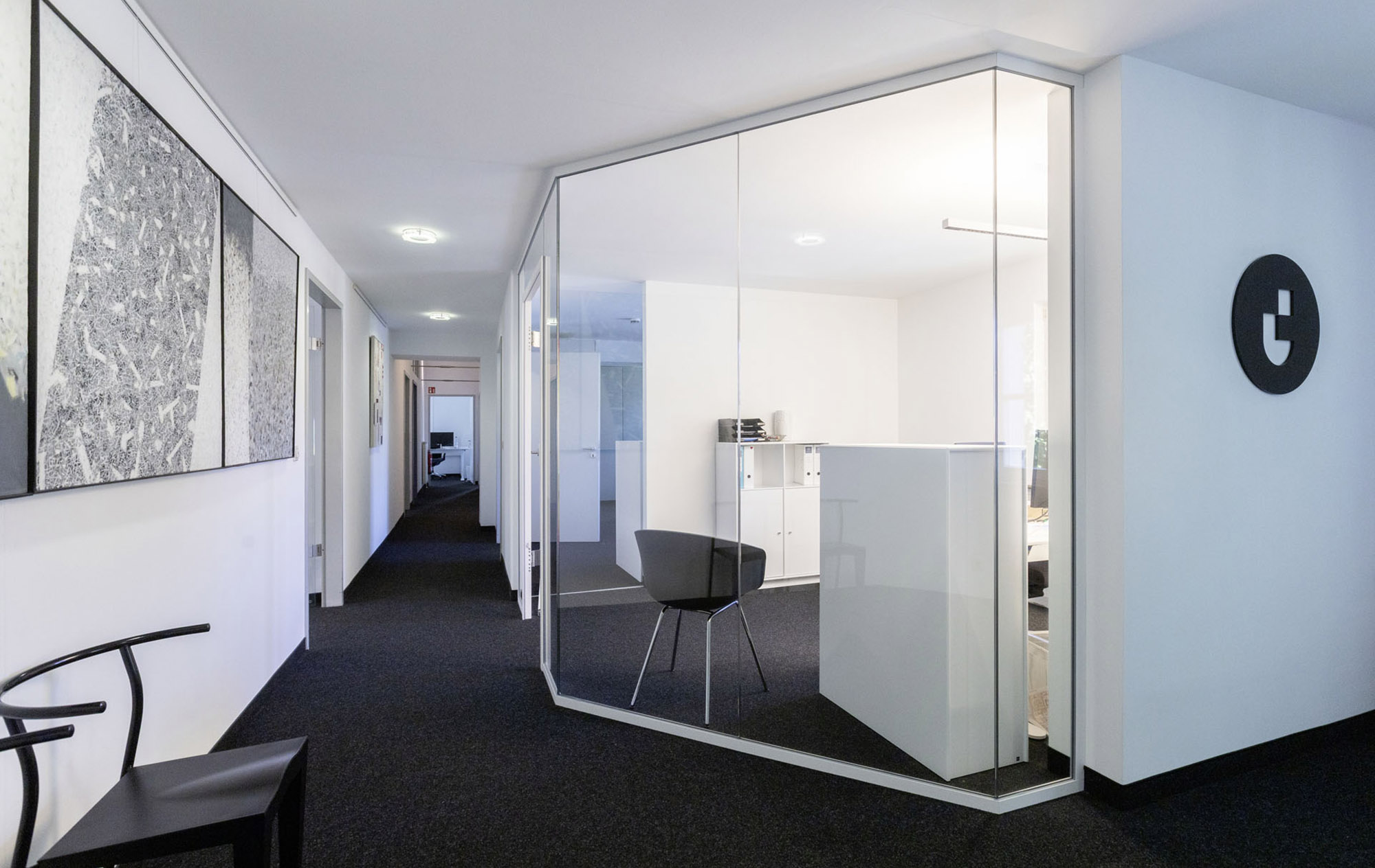 Moderner Büroflur mit verglastem Besprechungsraum und schlichtem Interieur.